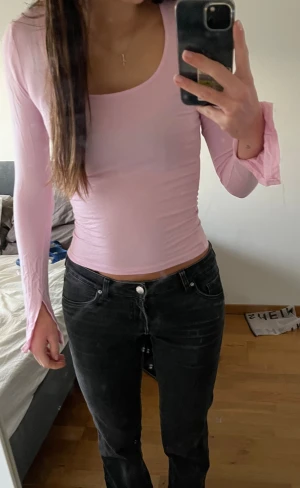 Ljusrosa långärmad topp med utsvängda ärmar - Säljer en ljusrosa långärmad topp med tight passform och utsvängda ärmslut. Toppen har en rundad, bred urringning och är gjord i ett mjukt, stretchigt material som sitter snyggt mot kroppen.