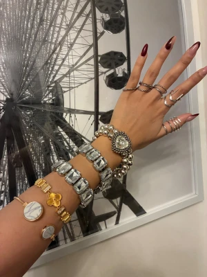 Mixade armband och ringar i silver och guld - Säljer ett set med flera armband och ringar. Armbanden är i silver och guld, vissa med stora glittriga stenar och ett med hjärtformad detalj. Två guldarmband har marmormönster och fyrklöver. Ringarna är i silver, olika former och bredder, vissa med twistad design. Perfekt för dig som gillar att mixa och matcha. Paketpris 299. Kontakta mig om du vill köpa styckvis och kom med prisförslag!💖