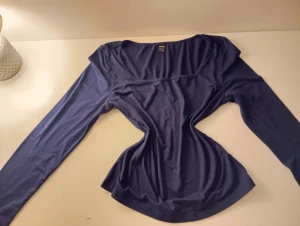 Mörkblå långärmad topp från SHEIN - Snygg mörkblå långärmad topp från SHEIN. Tunn och mjuk i stretchigt syntetmaterial, perfekt för att styla med jeans eller kjol. Enkel design med slim passform som framhäver siluetten.