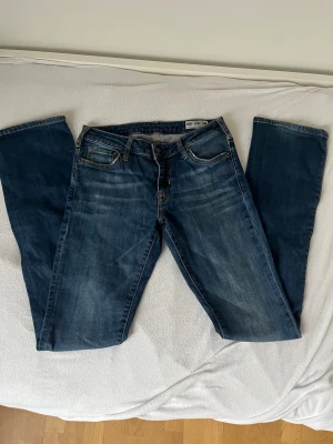 Mörkblå Crocker jeans - Snygga mörkblå jeans från Crocker med klassisk bootcut fit och fem fickor. Jeansen har kontrastsömmar, läderpatch med logga bak och är tillverkade i slitstarkt denim. Perfekt passform och tidlös look för dig som gillar enkel stil. Storlek xs-S PRISET KAN DISKUTERAS!!