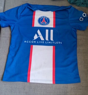 Paris Saint-German home shirt 2020/21 Vapor Neymar - Blå PSG fotbollströja med Neymar Jr och nummer 10 på ryggen. Tröjan har vita och röda vertikala ränder framtill, samt klubbmärke och sponsortryck. Kortärmad modell i lätt och ventilerande material, perfekt för match eller träning.