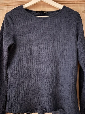 Mörkblå topp  - Mörkblå långärmad topp från lager 157 med Skönt material,Vågiga kanter nertill och vid ärmslut. Perfekt för dig som gillar en enkel men ändå unik look.