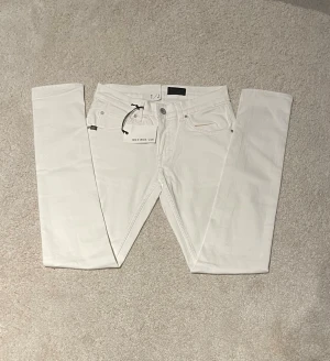 Vita jeans från Tiger of Sweden W29 L32 - Snygga vita jeans från Tiger of Sweden med normal passform. Klassisk femficksmodell med stilren design och diskret logga på bakfickan. Perfekta för dig som gillar en clean och modern look.