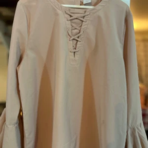 Ljusrosa skjorta med snörning och volangärm - Ljusrosa blus från Lindex jätte fin använd några gånger har små små fläckar som knappt syns och går säkert att ta bort  kom privat för bilder strö 170 