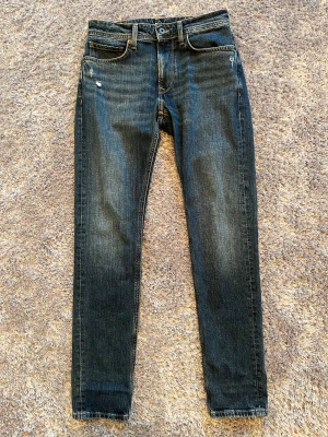 Pepe Jeans taperade jeans blå - Snygga blå jeans från Pepe Jeans med taperat snitt. Klassisk femficksmodell med läderpatch bak i midjan. Jeansen har en mörk tvätt med lätt slitning och är tillverkade i mjukt denimtyg. Perfekta för dig som gillar en smalare passform.