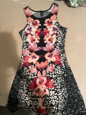 Blommig och leopardmönstrad klänning H&M - Supersnygg kort klänning från H&M i storlek XS med färgstarkt blommönster i rosa, lila och rött samt svartvitt leopardmönster. Ärmlös modell med rund halsringning och figurnära passform. Perfekt för dig som vill sticka ut med en unik look.