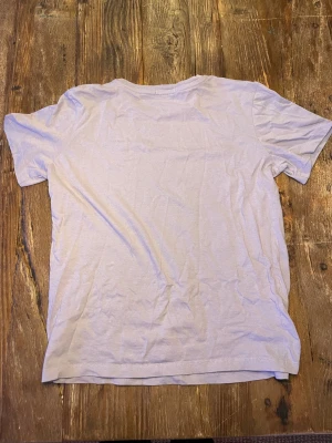 Ljuslila t-shirt från Calvin Klein Jeans - Snygg ljuslila t-shirt från Calvin Klein Jeans med diskret logga på bröstet och ett litet tryck på ärmen. Klassisk rund hals och korta ärmar. Mjuk och skön bomull som passar perfekt till jeans eller shorts. Enkel och stilren design för en chill look.