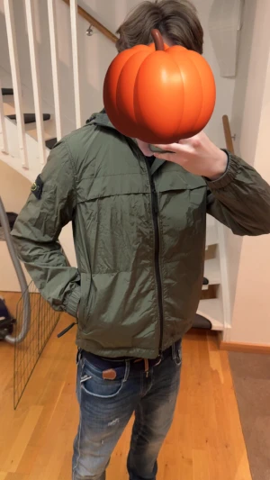 Stone Island grön vindjacka med huva - Snygg grön vindjacka från Stone Island med ikonisk patch på vänster ärm. Jackan har huva, dragkedja framtill och elastiska muddar. Tillverkad i 100% återvunnen nylon med vattenavvisande och vindtät yta. Perfekt för dig som gillar streetwear och vill ha en clean look. 