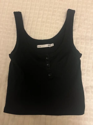 Svart ribbad linne - Svart croppad linnetopp från i ribbad bomull med rundad hals och tre knappar framtill. Extremt bra skick!! 