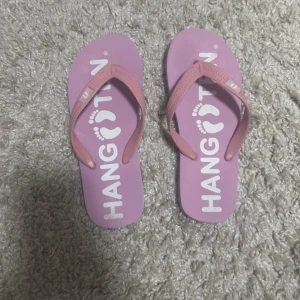 Rosa flip-flops - Ett par rosa flip-flops med fotavtryck på sulan