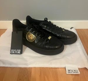 Svarta sneakers Versace Jeans Couture - Säljer dessa Versace Jeans Couture skor i storlek 44 då de aldrig kommer till användning! Skorna är aldrig använda, med både prislapp och påse som följer med! Nypris ca 2 500kr-3 000kr Hör av er vid frågor! Pris kan diskuteras 