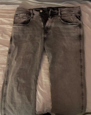 Replay Anbass grå jeans, W31 L30 - Snygga Replay Anbass jeans i en tvättad grå färg med klassisk femficksdesign och svarta Replay-detaljer vid fickan. Jeansen har rak passform och är tillverkade i mjukt jeanstyg som sitter skönt hela dagen. Köpte dom nya på Johnells för typ 3 månader sen.