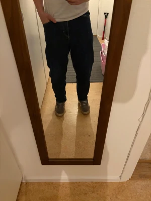 Mörkblå raka jeans - Säljer ett par mörkblå jeans med klassisk rak passform och fem fickor. Jeansen har normal midja och är tillverkade i slitstarkt denimtyg. Perfekt för dig som gillar en enkel och tidlös stil.