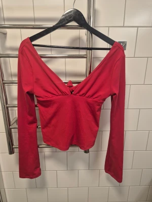 Röd topp med knyt från Nelly - Snygg röd topp från Nelly med knyte där bak. Köpt för lite mindre än ett år sen men aldrig använd. 