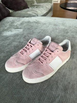 Rosa Valentino flycrews - Snygga sneakers från Valentino i ljusrosa mocka med vita detaljer och vit sula. Klassisk låg modell med rosa skosnören och logga på plösen. Perfekta för dig som vill ha en stilren och trendig look med exklusiv känsla. Låda och dust bag får du med ( de är även impregnerade)