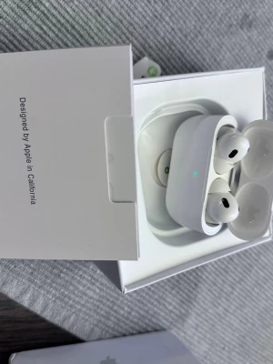 Apple AirPods med laddningsetui - Säljer ett par vita Apple AirPods med trådlöst laddningsetui. Snygg och stilren design i blank plast, perfekt för dig som vill ha smidiga och trådlösa hörlurar till mobilen. Kommer i originalförpackning.
