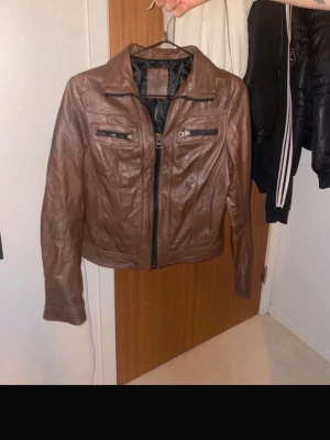 2000tals Brun skinnjacka - Jätte snygg brun skinnjacka väldigt 2000tal i otroligt bra skick! Står ingen storlek men är lite för liten för mig och jag bär S/M så skulle säga att den är en XS? Skriv gärna vid fler frågor. Köpt secondhand för 250kr PRIS GÅR ALLTID ATT DISKUTERA!                        SKRIV INNAN DU KÖPER!!!