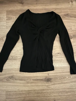 Svart ribbad långärmad topp -  svart ribbad topp med lång ärm och twistad detalj framtill. Aldrig andvänt 