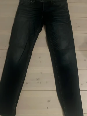 Mörkblå jeans Jack & Jones Comfort Mike - Säljer ett par svarta jeans från Jack & Jones, modell Comfort Mike. Jeansen har fem fickor, knappgylf och diskreta slitningar för en cool look. Materialet är mjukt och stretchigt för extra komfort. Perfekta för dig som gillar en avslappnad men snygg stil.