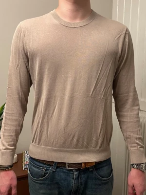 Beige tunn långärmad tröja - Säljer en stilren beige långärmad tröja från Riley. Tröjan är av 100% bomull. 