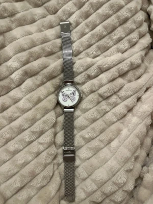 Daniel Klein klocka med fjärilsmotiv - silvrig klocka från Daniel Klein med mesh-armband i rostfritt stål. Urtavlan är vit med ett stort lila fjärilsmotiv och minimalistiska markeringar. Batteriet behövs bytas ut!