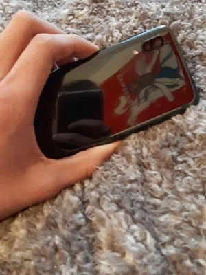 Samsung Galaxy svart Android-mobil - Snygg svart Samsung Galaxy Android-telefon med glansig baksida, dubbla kameror och fingeravtrycksläsare på baksidan. Telefonen har rundade hörn och en stilren design i plast och glas. Perfekt för dig som vill ha en pålitlig smartphone med modern look.