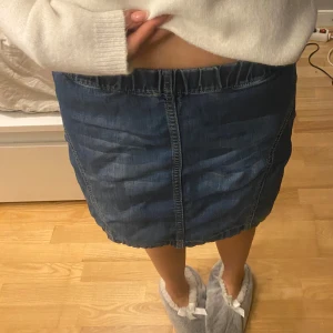 Blå denim mini skirt - Säljer en snygg blå jeanskjol. Kjolen har en enkel design med synliga sömmar och elastisk midja💗kjolen finns ej i ginas sortiment längre