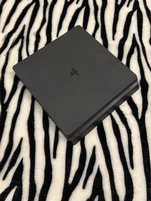 PlayStation 4 Slim spelkonsol svart - Säljer en svart PlayStation 4 Slim från Sony. Med allt du kräver Max 6st kontroller 1=150 om du ska + på sedan strömsladd, laddarsladd och HDMIslad följer med och sist den är restartd ska funka bra 👍 