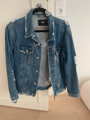 Jeansjacka Bikbok - Blå jeansjacka med slitningar från Bik Bok, storlek XS, använd flera gånger men i bra skick. Slitningarna var där vid inköp, den är gjord så.