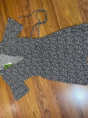 Blåa blommig omlottklänning - Blåa kort omlottklänning från Monki med vitt blommönster. Klänningen har korta ärmar, knytband i midjan och v-ringad hals. Perfekt för dig som gillar en feminin och trendig stil.