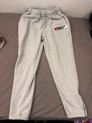 Gråa mjukisbyxor Artstart - Säljer ett par gråa mjukisbyxor från trapstar med broderad logga i rött, svart, grått och vitt på vänster sida. 