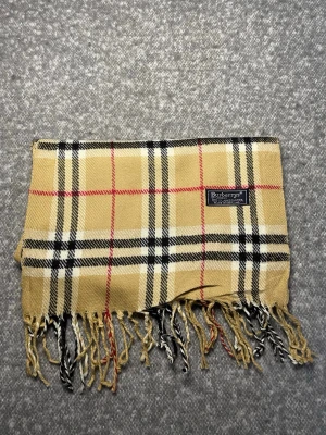 Burberry Halsduk Beige - Klassisk Burberry-halsduk i 100 % lammull. Mjuk och varm med tidlöst rutmönster i beige, svart, vitt och rött. Originaletikett, Made in England. 3B