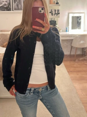 Svart klassisk kofta med knappar - En mörkblå enkel och klassisk kofta med knäppning framtill. Långärmad och rak modell som passar till det mesta. Perfekt att slänga över en t-shirt eller linne!!