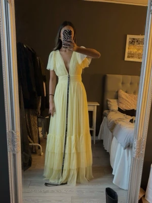 Ljusgul långklänning med volang - Säljer en ljusgul balklänning med djup v-ringning och volanger. Slutsåld på hemsidan. Passar 32-36