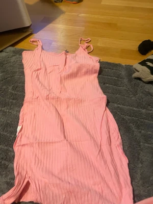 Rosa ribbad klänning från SHEIN - Säljer en söt rosa ribbad klänning från SHEIN i storlek XS. Klänningen är kort, har smala axelband och en figurnära passform. Perfekt för varma dagar och enkel att styla med sneakers eller sandaler.