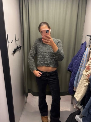 Grön fluffig cropped stickad tröja - Mysig grön stickad tröja med fluffig textur och croppad passform. Tröjan har långa ärmar och en avslappnad siluett, perfekt för en trendig och bekväm look. Inget synligt märke.