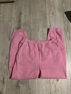 Rosa mjukisbyxor med resårmidja - Säljer ett par rosa mjukisbyxor med avslappnad passform och resår i midjan. Byxorna har raka ben och är tillverkade i mjukt bomullsliknande material. Perfekta för chill dagar eller när du vill vara extra bekväm.