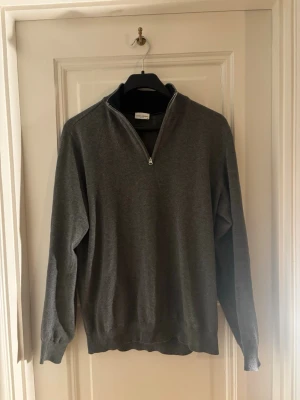 Grå halvzip tröja från John Henric - Snygg grå tröja från John Henric med halvzip och ståkrage. Tillverkad i mjukt material som känns skönt mot huden. Perfekt till lager på lager och enkel att matcha med olika outfits. Klassisk passform och ribbade muddar vid ärmslut och nederkant. En modell som funkar både casual och uppklätt. Tveka inte att höra av dig vid eventuella frågor eller pris! 