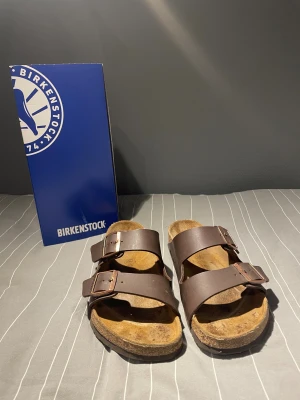Bruna Birkenstock arizona  - Klassiska Birkenstock arizona i gott skick endast använda några gånger i somras. Perfekta under sommaren men också på vintern som inneskor! Såklart helt äkta köpta på zalando