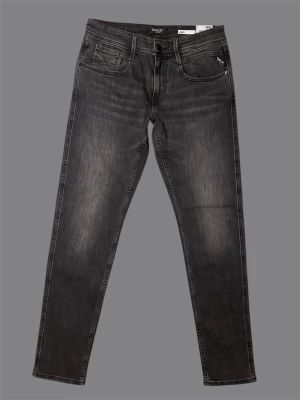 Replay svarta slim fit jeans - Snygga svarta jeans från Replay i anbass slim fit-modell. Jeansen har klassisk femficksdesign, diskreta slitningar och Replay-logga på fickan. Materialet är mjukt denim med lite stretch för extra komfort. Perfekta för dig som gillar en modern och stilren look.