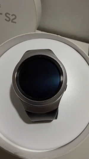 Samsung Gear S2 med extra armband - Samsung Gear S2 smartwatch med rund silverfärgad boett i rostfritt stål och svart silikonarmband. Flera utbytbara armband i rött, blått, beige och metall ingår. Modern design och smidig storlek, perfekt för dig som gillar att byta stil på din klocka.