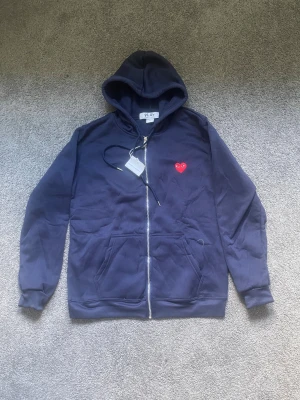 Cdg zip hoodie - Säljer en riktigt snygg hoodie från cdg helt oanvänd och e skön. Hör av er vid mer frågor:)
