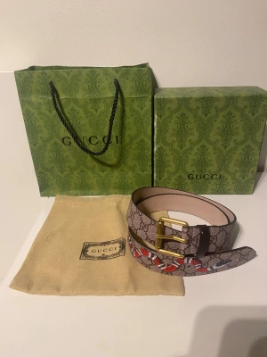  GG Supreme bälte med orm - Säljer ettGG Supreme bälte i beige med klassiskt monogrammönster och en röd orm-detalj. Bältet har ett guldfärgat spänne och är tillverkat i skinn. Kommer med originalpåse och förpackning.