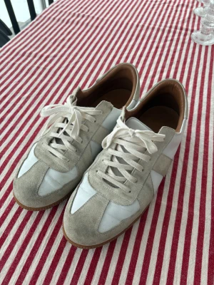 GAT-sneakers - Snygga GAT sneakers i vit och beige färg med klassisk design. Skorna har ovandel i vitt skinn och beige mocka. Bortsett från från den smutsiga mockan har skorna inga andra flaws, hör av er vid fler frågor eller bilder. Kommer med extra snören, dustbag och box. Pris kan diskuteras!