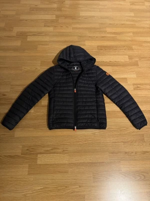 Svart pufferjacka Save The Duck - Säljer en svart dunjacka från Save The Duck med huva och hel dragkedja. Storlek M men passar S. Nypris ca 2500kr. Mycket bra skick, hör av dig vid fler frågor.