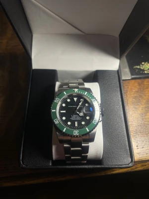 Seiko ”Starbucks” Mod - Helt nybyggd Seiko ”Starbucks” Mod  Specifikationer: Storlek: 40mm Urverk: Nh35 (Automatiskt) Material: 904L Rostfritt Stål Glas: Sapphire Glas Tavla: Svart  Bezel: Grön Armband: Viklås och Justerbart  Krona: Screw Down Vattentålighet: 30 Meter Klocklåda ingår