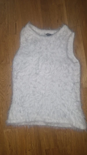 Vit fluffig stickad linnetopp Lindex - Supermysig vit stickad linnetopp från Lindex i storlek S. Toppen är ärmlös och har en fluffig, mjuk yta som ger en cool och trendig vibe. Perfekt att styla med jeans eller kjol för en chill look. Rund halsringning och rak passform.vill inte ha kvar den för den är inte riktigt min stil(om priset inte direkt passar dig kan vi ta ett annat pris!🤍)