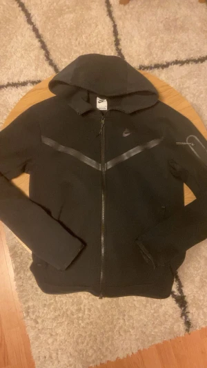 Svart Tech Fleece - Tjena👋 Säljer nu denna riktigt clean Nike Tech Fleece då den bara samlar damm i garderoben! Det finns inga defekter och det är extremt bra kvalitet🙌 Den är köpt från Zalando för ungefär 1300kr💸 Meddela gärna vid frågor!
