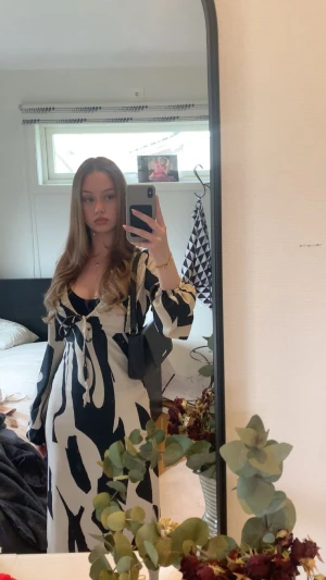 Långklänning med svartvitt mönster - Säljer en långklänning med svart och vit abstrakt design. Klänningen har långa ärmar, v-ringning och snörning framtill. Materialet känns mjukt och flowy, perfekt för dig som gillar statement-plagg med coola kontraster.