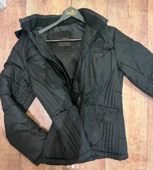 Svart snygg jacka🔥 - Säljer en svart pufferjacka från True Spirit med quiltade detaljer, hög krage och praktiska fickor med lock. Jackan har dragkedja framtill och lång ärm. Perfekt för kalla dagar och har en snygg, enkel look.